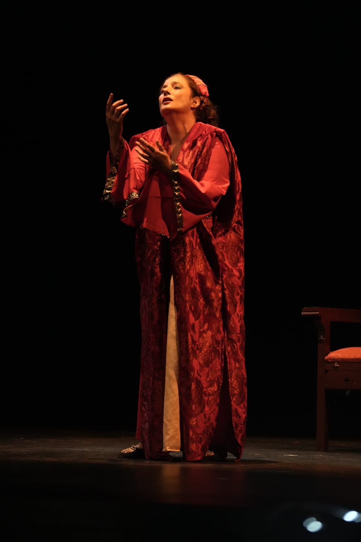 Vanessa Ayllón cantando sola en el escenario, vestida de rojo