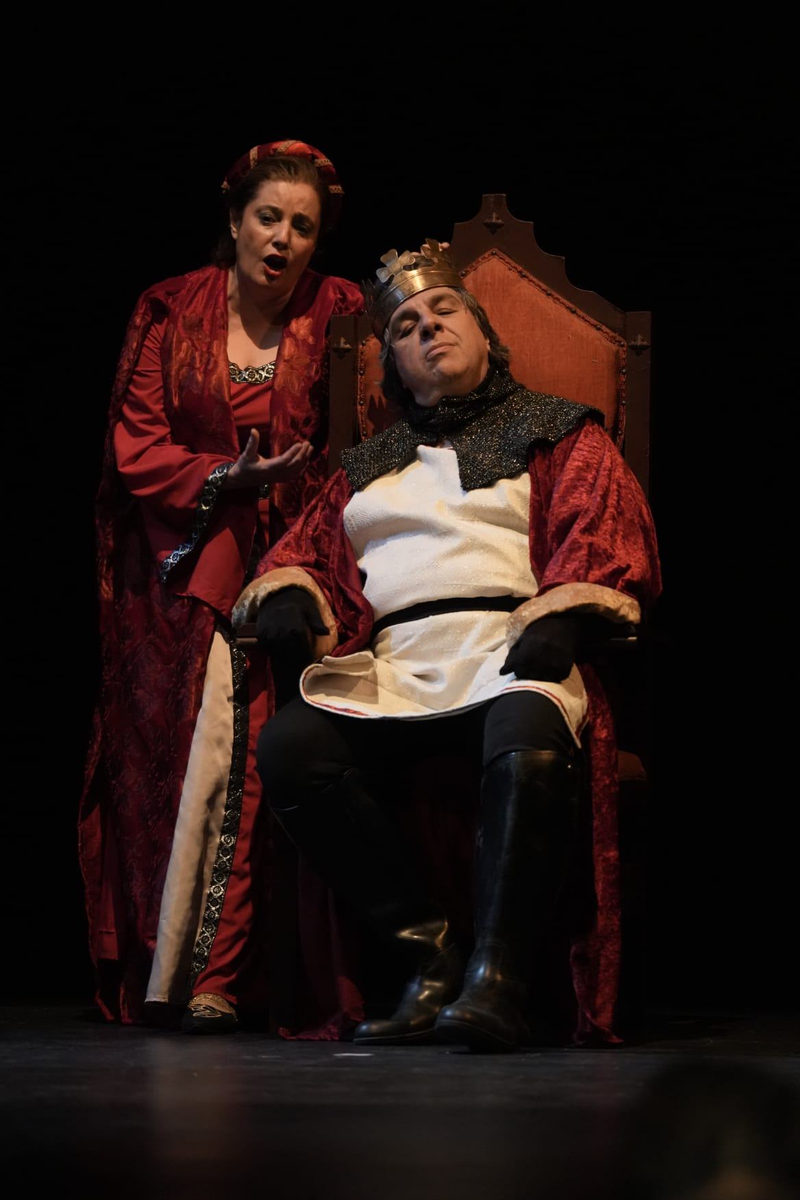 Escena de ópera con Vanessa Ayllón y otros intérpretes con vestuario rojo