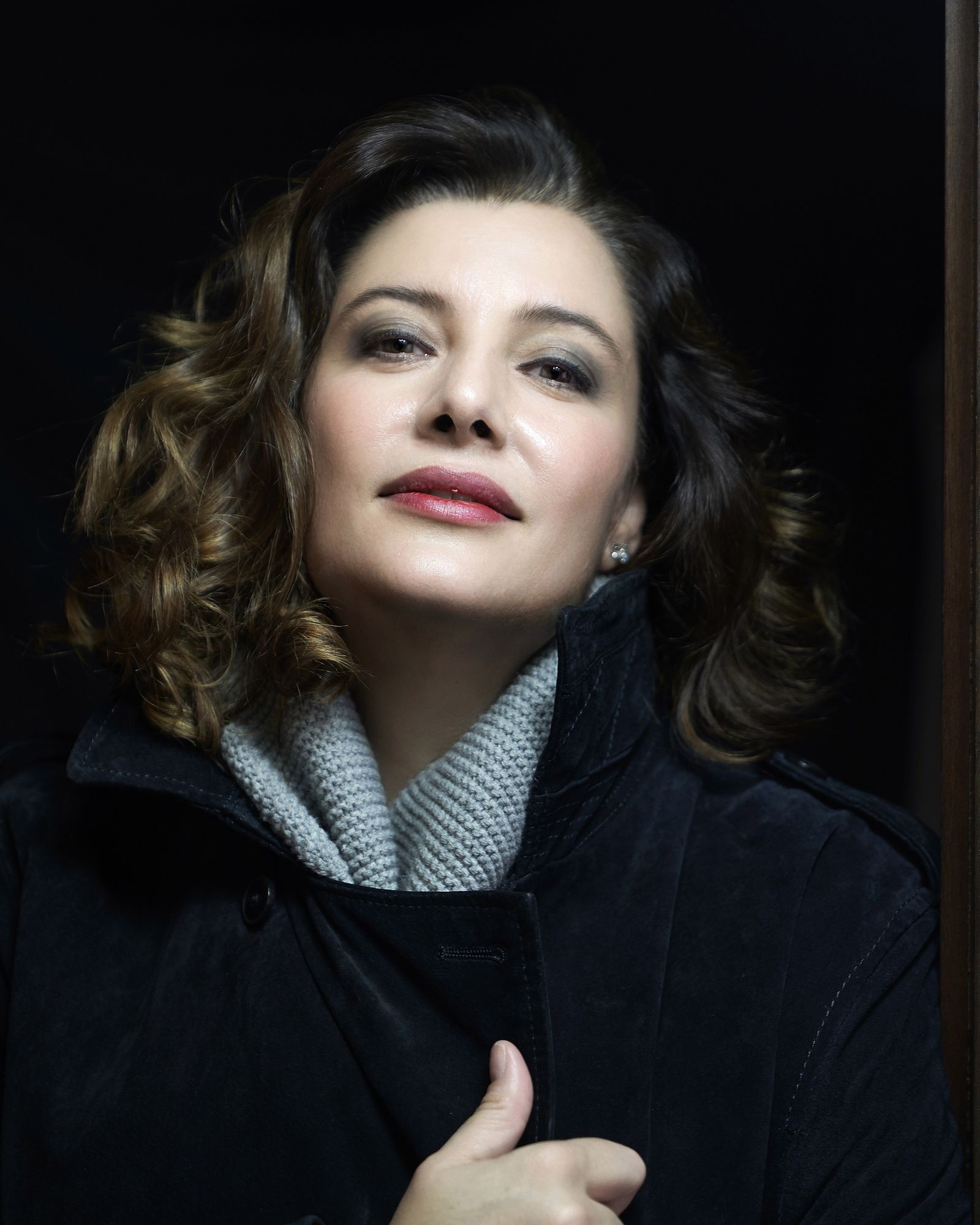 Retrato de la soprano Vanessa Ayllón, de abrigo oscuro, iluminada lateralmente
